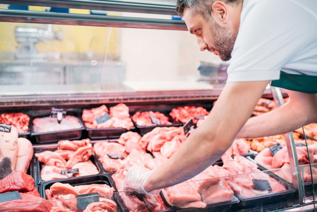 shop assistant in apron assorting fresh raw meat i 2023 11 27 05 37 05 utc